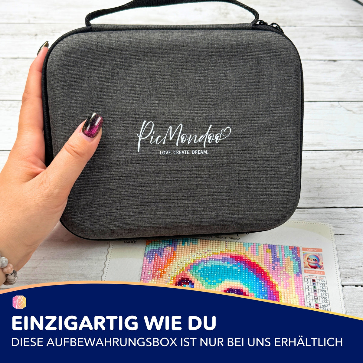 Graue Picmondoo Aufbewahrungsbox für E-Painter Zubehör neben einem bunten Diamond Painting Set auf weißem Holztisch.