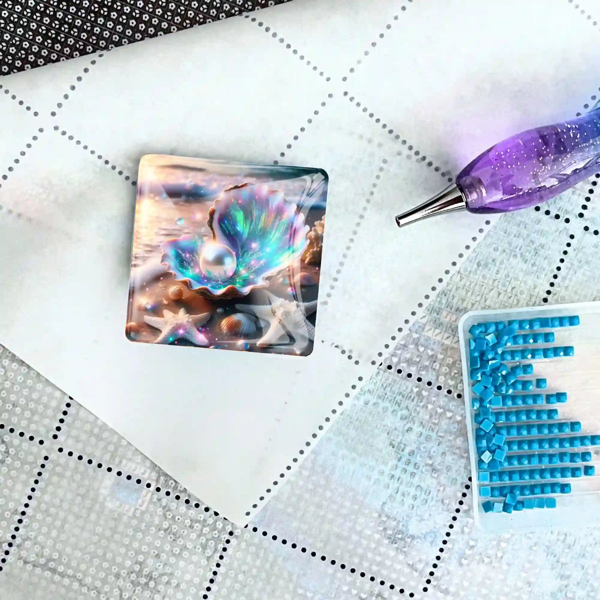 Magischer Cover Minder mit Muschel-Motiv als praktisches Zubehör für Diamond Painting auf einer Leinwand