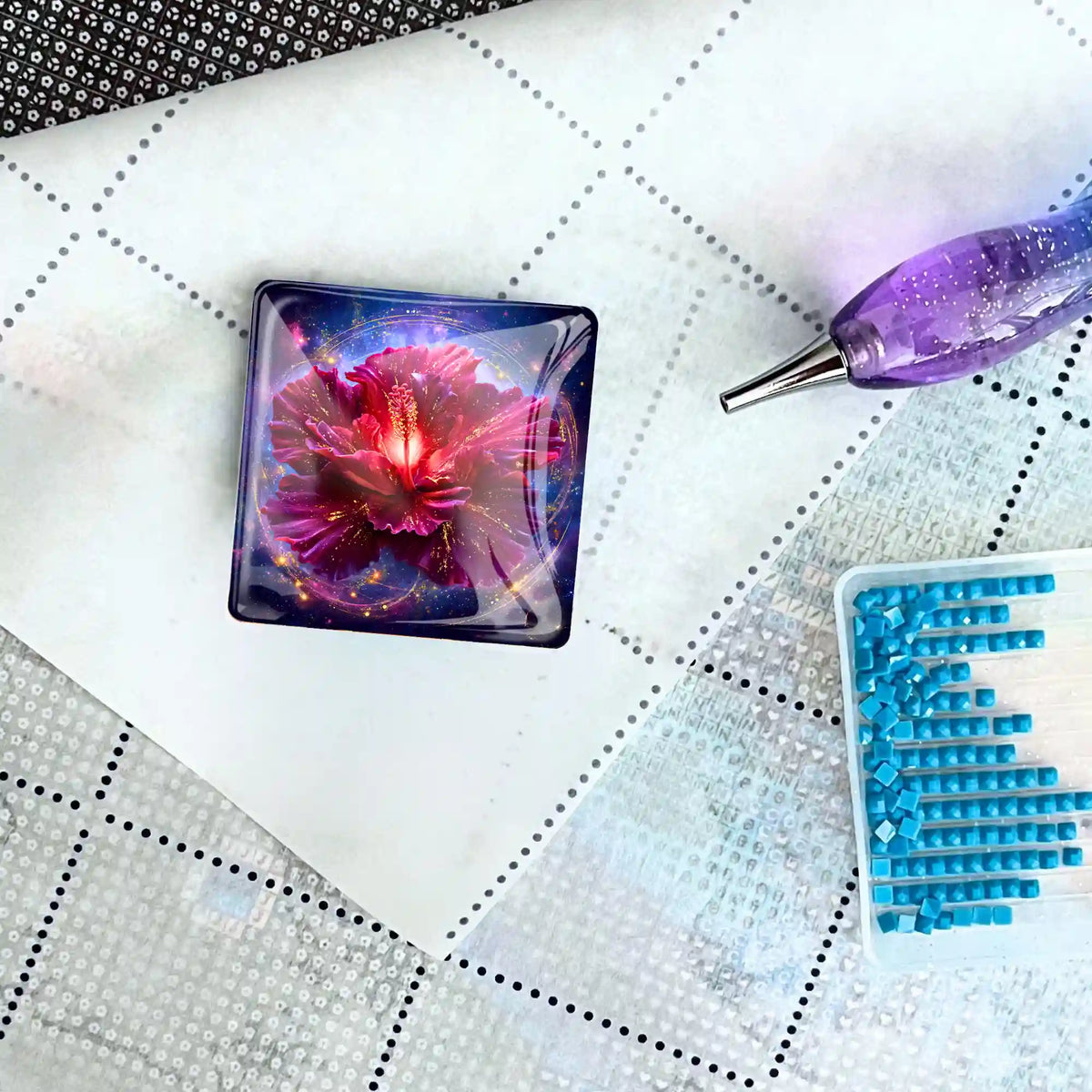Quadratischer Diamond Painting Cover Minder mit Blüten-Motiv auf einer Leinwand mit Pen und Steinchen-Schale