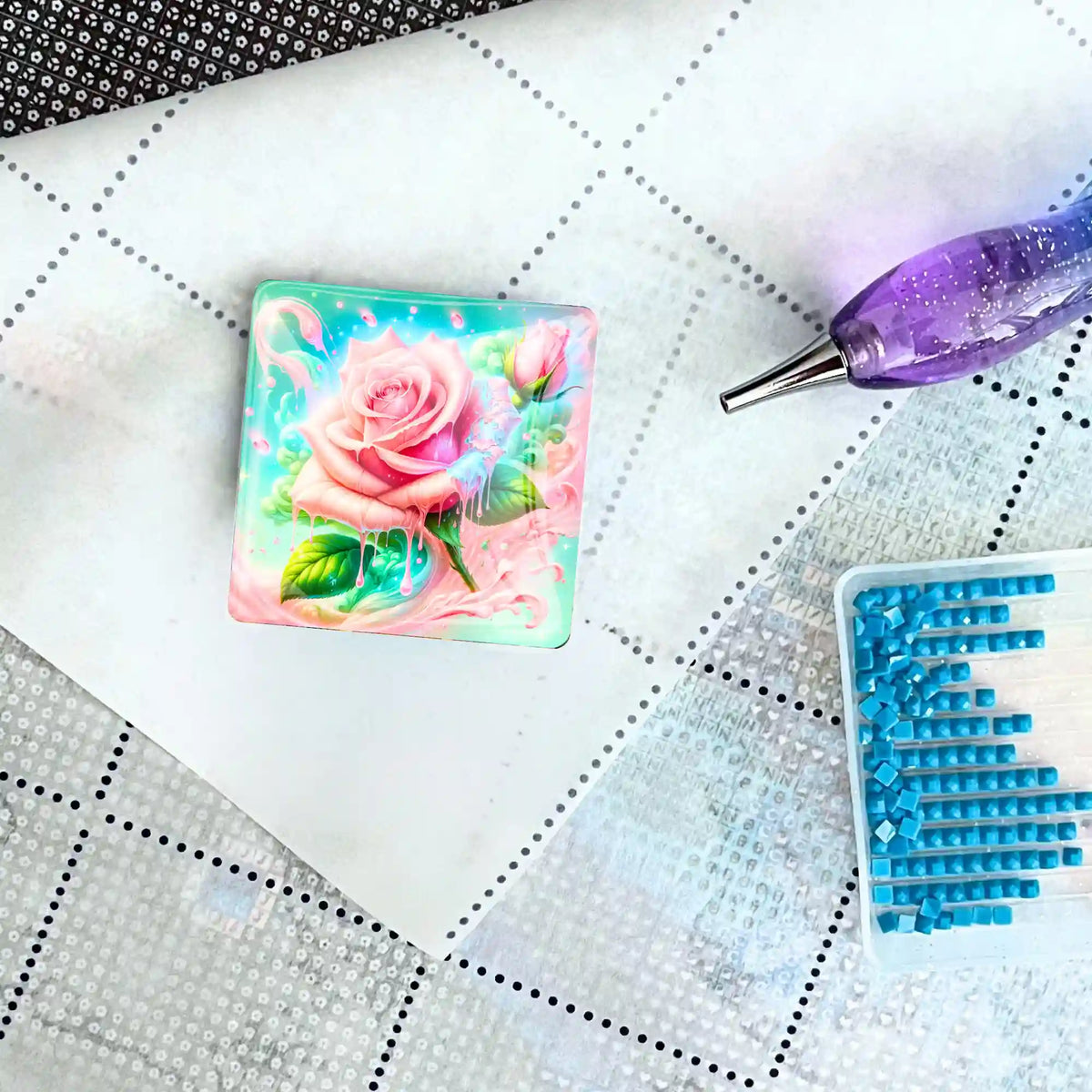 Quadratischer Candy Rose Cover Minder aus Glas auf einer Diamond Painting Leinwand mit Stift und blauen Diamanten