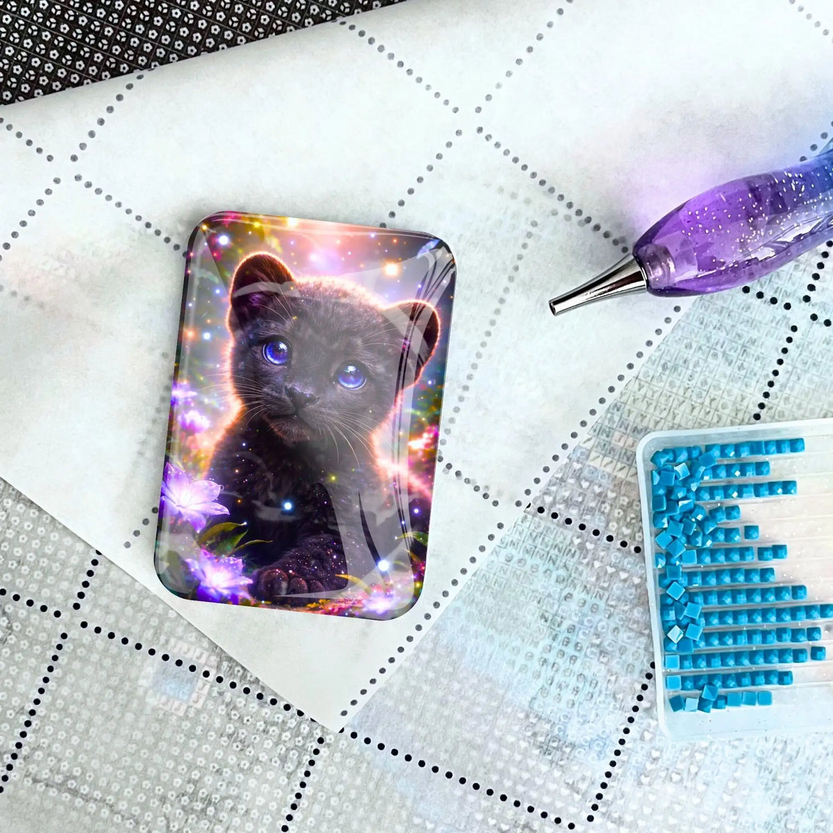 Glas Cover Minder mit Panther-Motiv auf Diamond Painting Leinwand neben Glitzersteinen und Zubehörstift