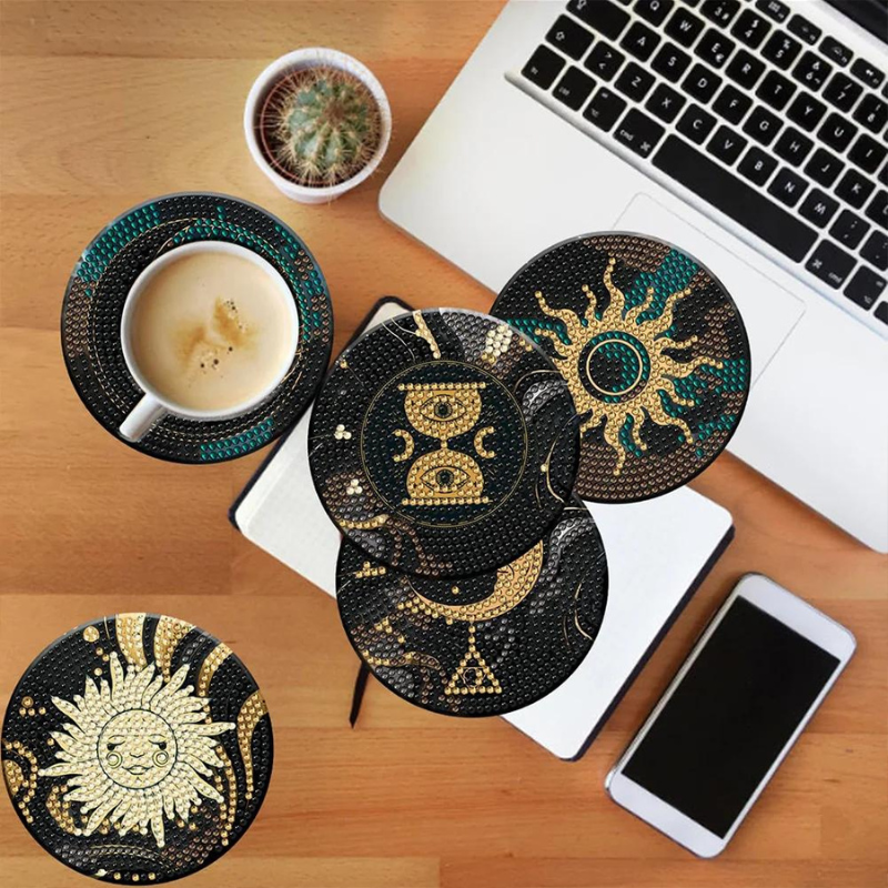 Diamond Painting Untersetzer Black Dream mit Sonne und Goldmustern aus funkelnden Strass Steinen auf einem Schreibtisch