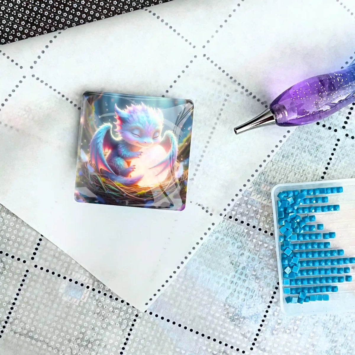 Glas Cover Minder mit Lichtdrache Faye auf einer Diamond Painting Leinwand mit Glitzersteinchen und Stift.