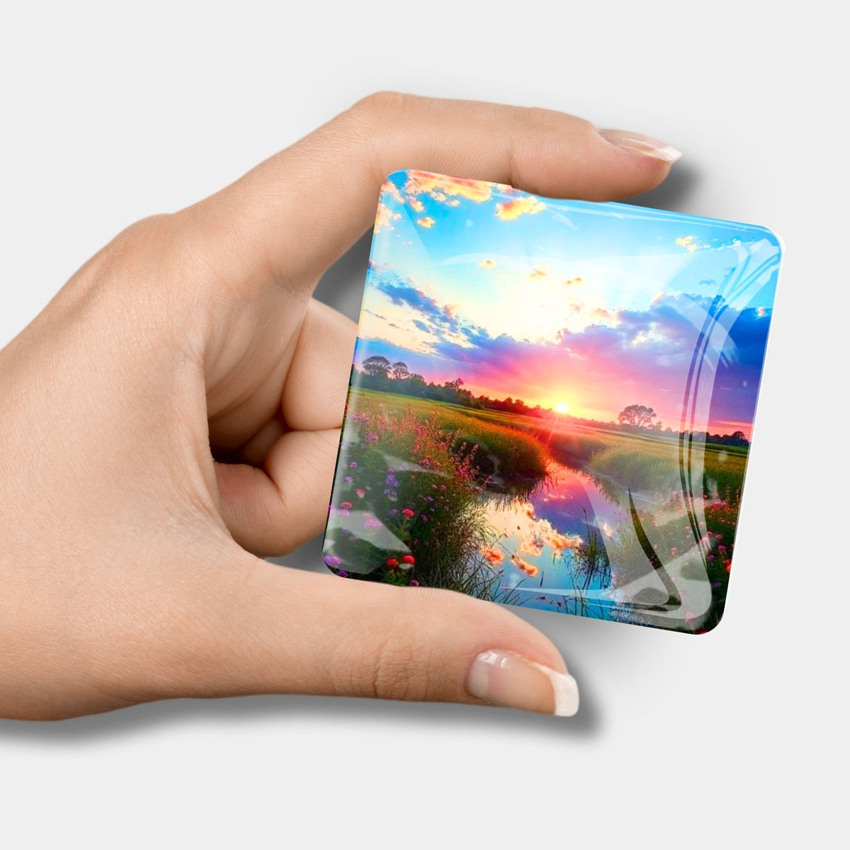 Quadratischer Diamond Painting Cover Minder Morgenrot mit Sonnenuntergang-Motiv, gehalten in einer Hand.