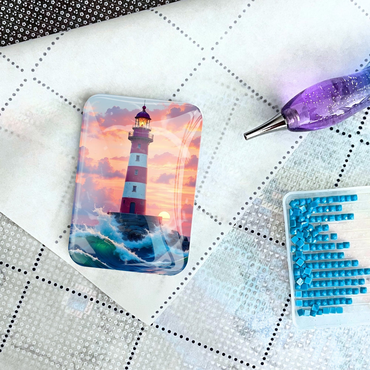 Diamond Painting Cover Minder mit Leuchtturm-Motiv auf einer Leinwand mit Applikator und blauen Steinchen