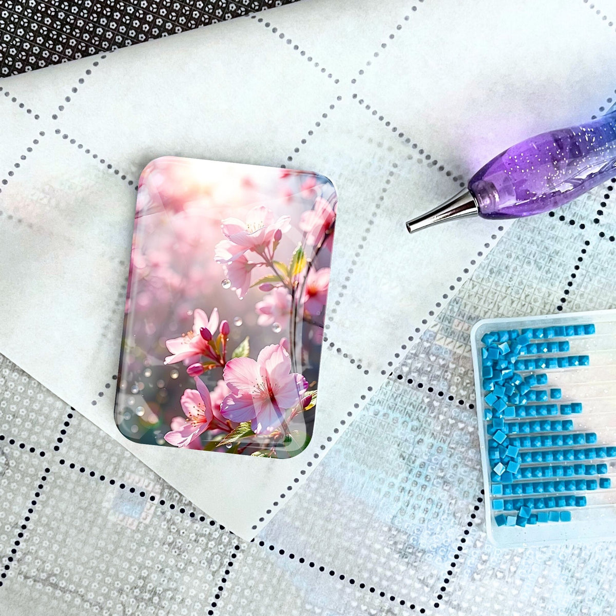 Kirschblüten Cover Minder als magnetischer Halter für Diamond Painting auf einer Leinwand mit Stift und Steinchen.