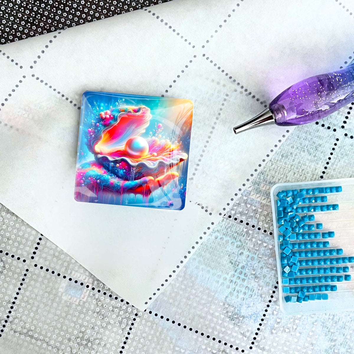 Quadratischer Diamond Painting Cover Minder Zauber des Meeres mit Muschel-Motiv auf einer Leinwand mit Stift und Steinchen.