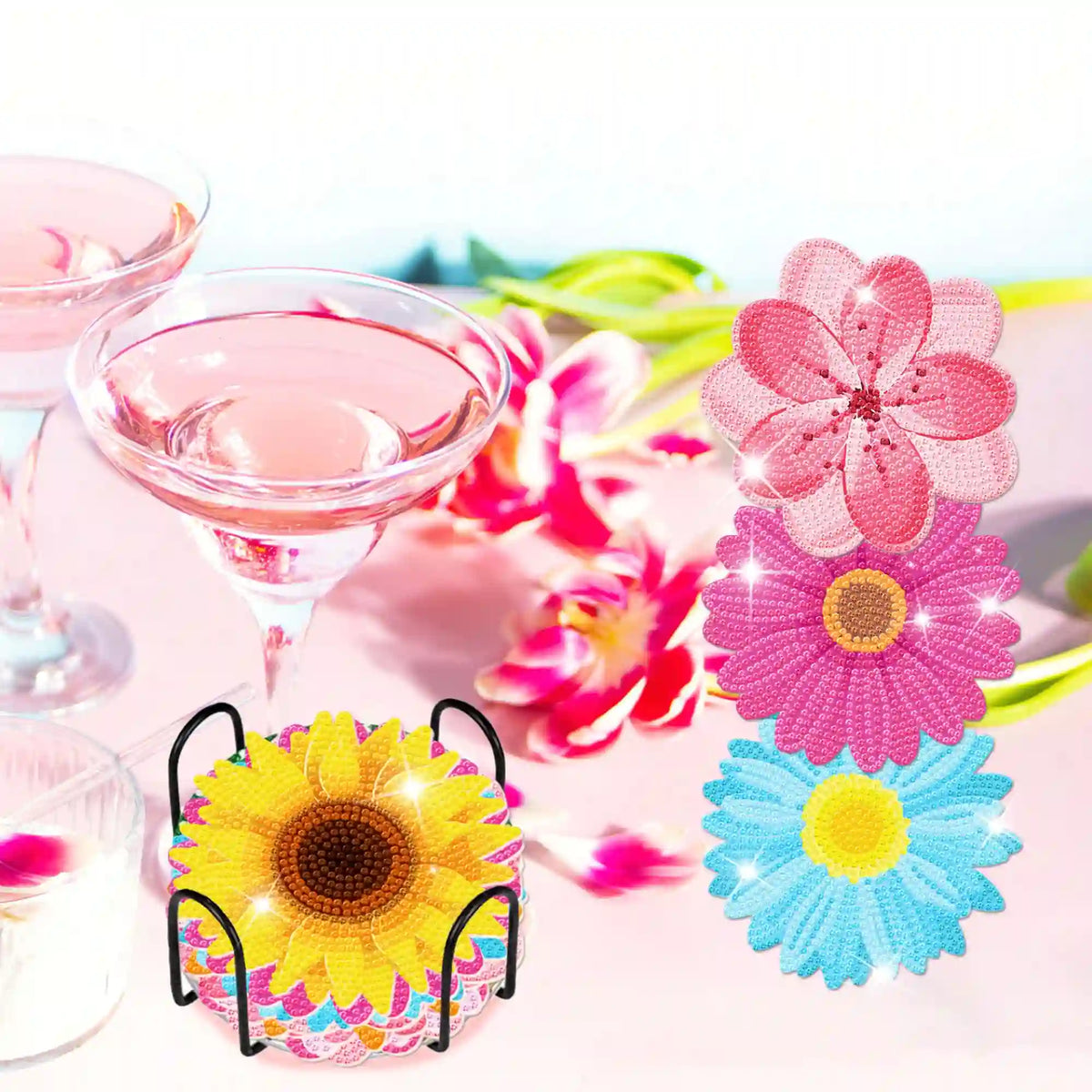 Diamond Painting Untersetzer mit Blumenmotiv aus glitzernden Steinen im schwarzen Halter neben Blumen und Weingläsern