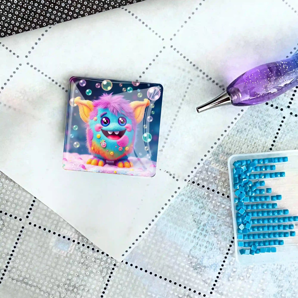 Bunter Grinsebacke Cover Minder aus Glas auf einer Diamond Painting Leinwand mit Stift und blauen Diamanten