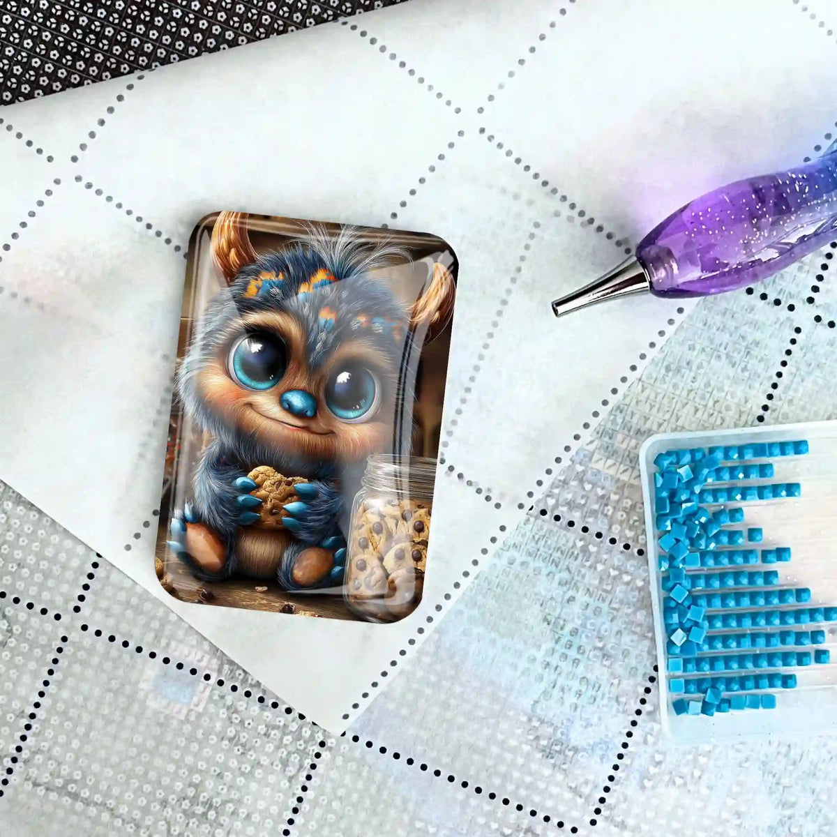 Diamond Painting Cover Minder Motiv süßes Monster mit Keks auf einer Leinwand mit Werkzeug