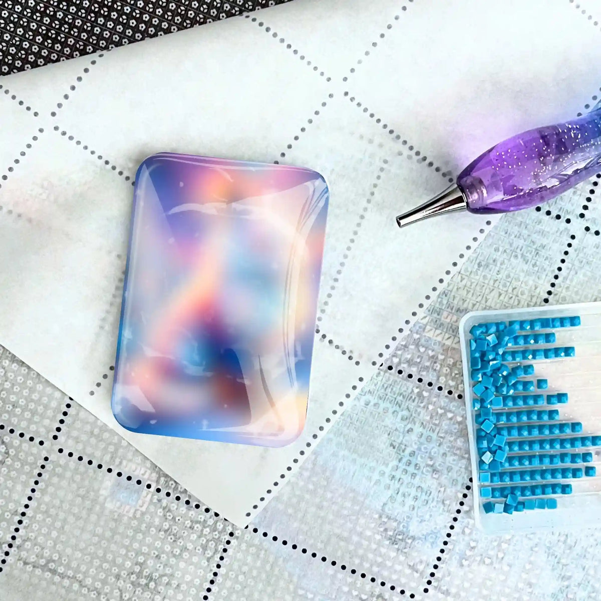 Bunter Diamond Painting Cover Minder auf Leinwand mit Glitzer-Stift und blauem Steinchen-Set als hilfreiches Accessoire
