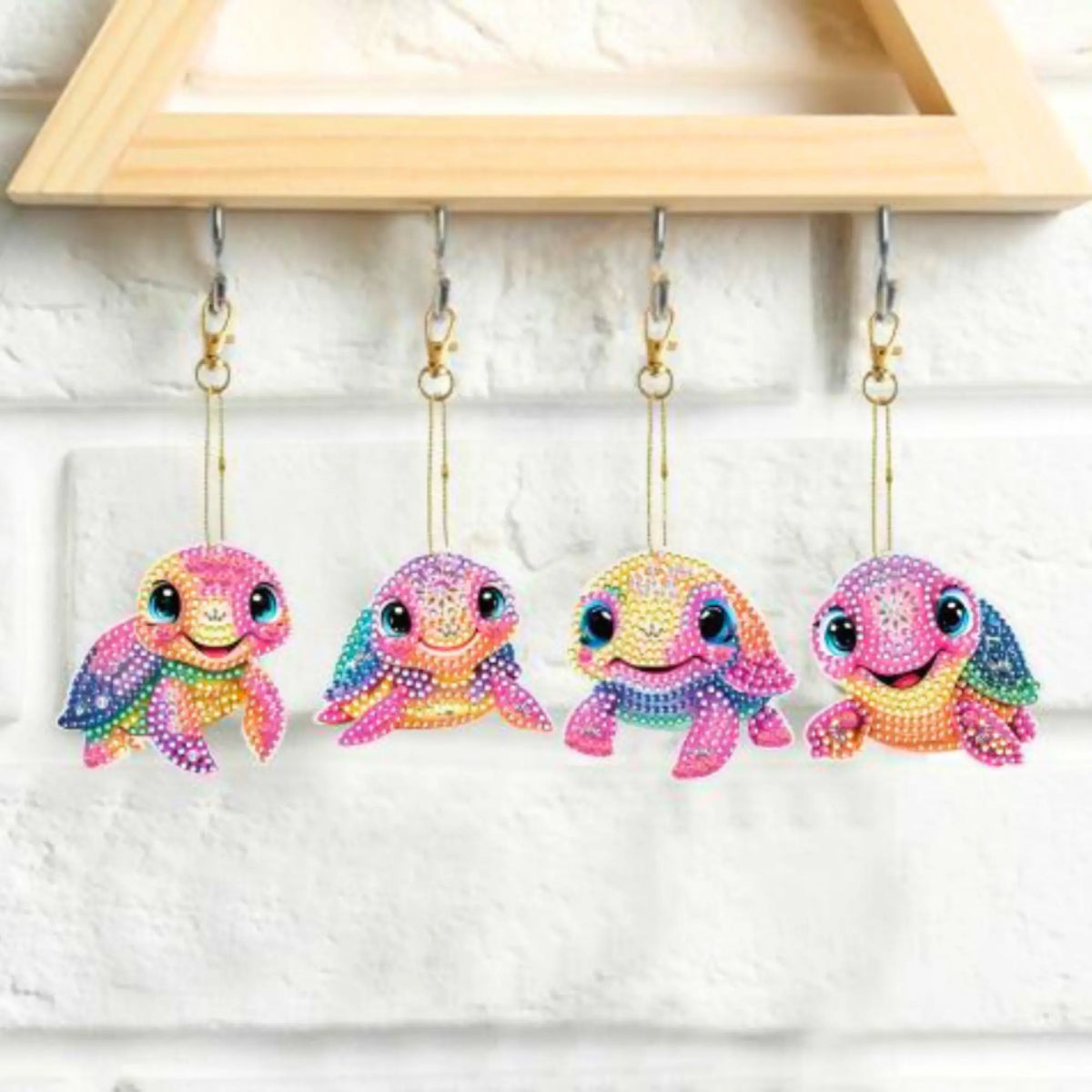 Set aus vier bunten Schildkröten Diamond Painting Schlüsselanhängern mit glitzernden Steinchen an einem Schlüsselbrett