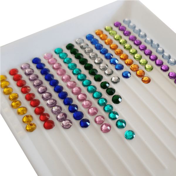 Bunte Diamond Painting Steine in einer weißen Sortierschale für Schmetterlings Sticker und DIY-Projekte