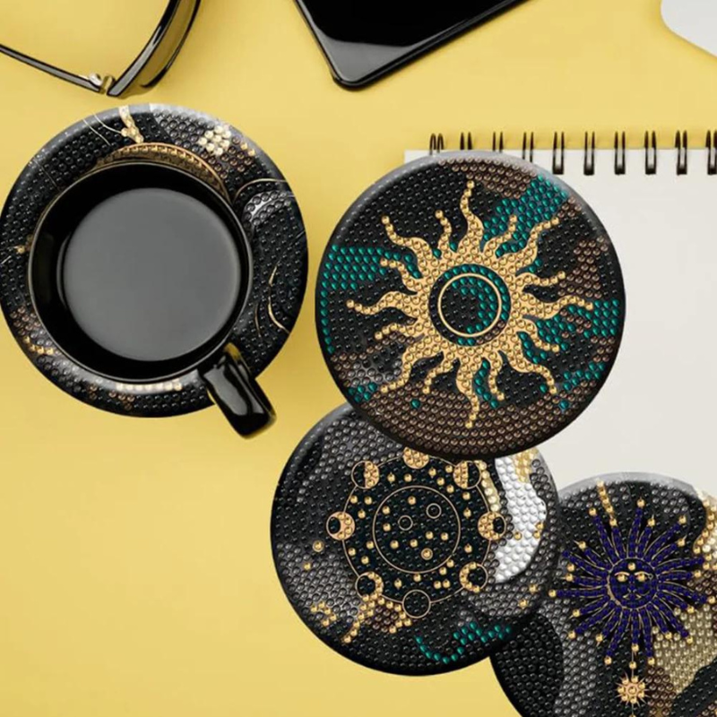 Diamond Painting Untersetzer Black Dream Set mit glitzernden Sonnen-Motiven in Schwarz und Gold auf gelbem Hintergrund