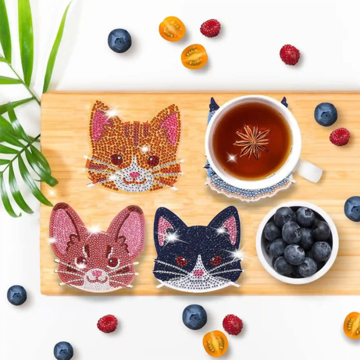Diamond Painting Untersetzer Set Katz und Maus mit funkelnden Strass Steinen auf Holztisch mit Tee und Beeren