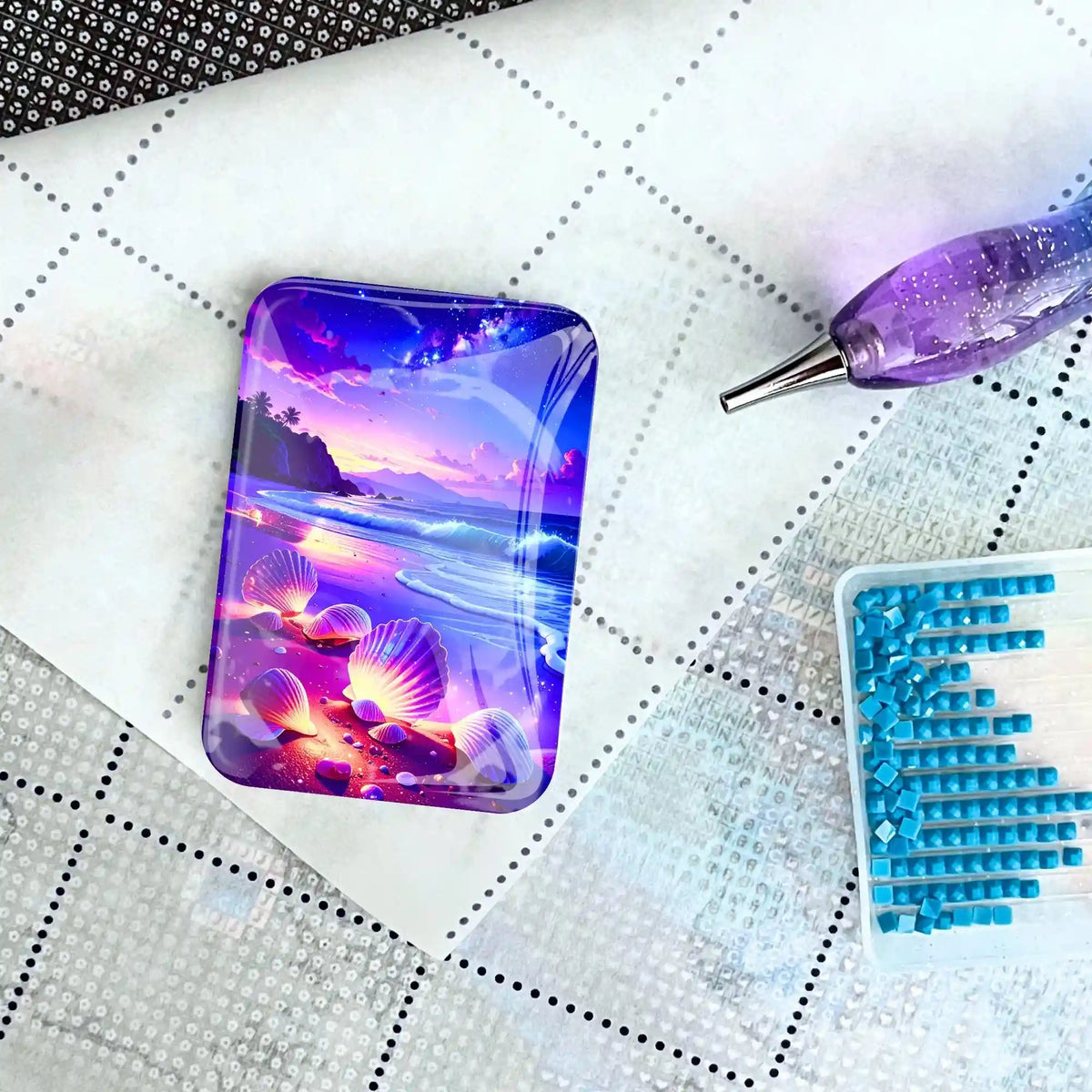 Glas-Coverminder Wunschmuscheln als praktisches Zubehör für Diamond Painting auf einer Leinwand mit Stift und Steinen.