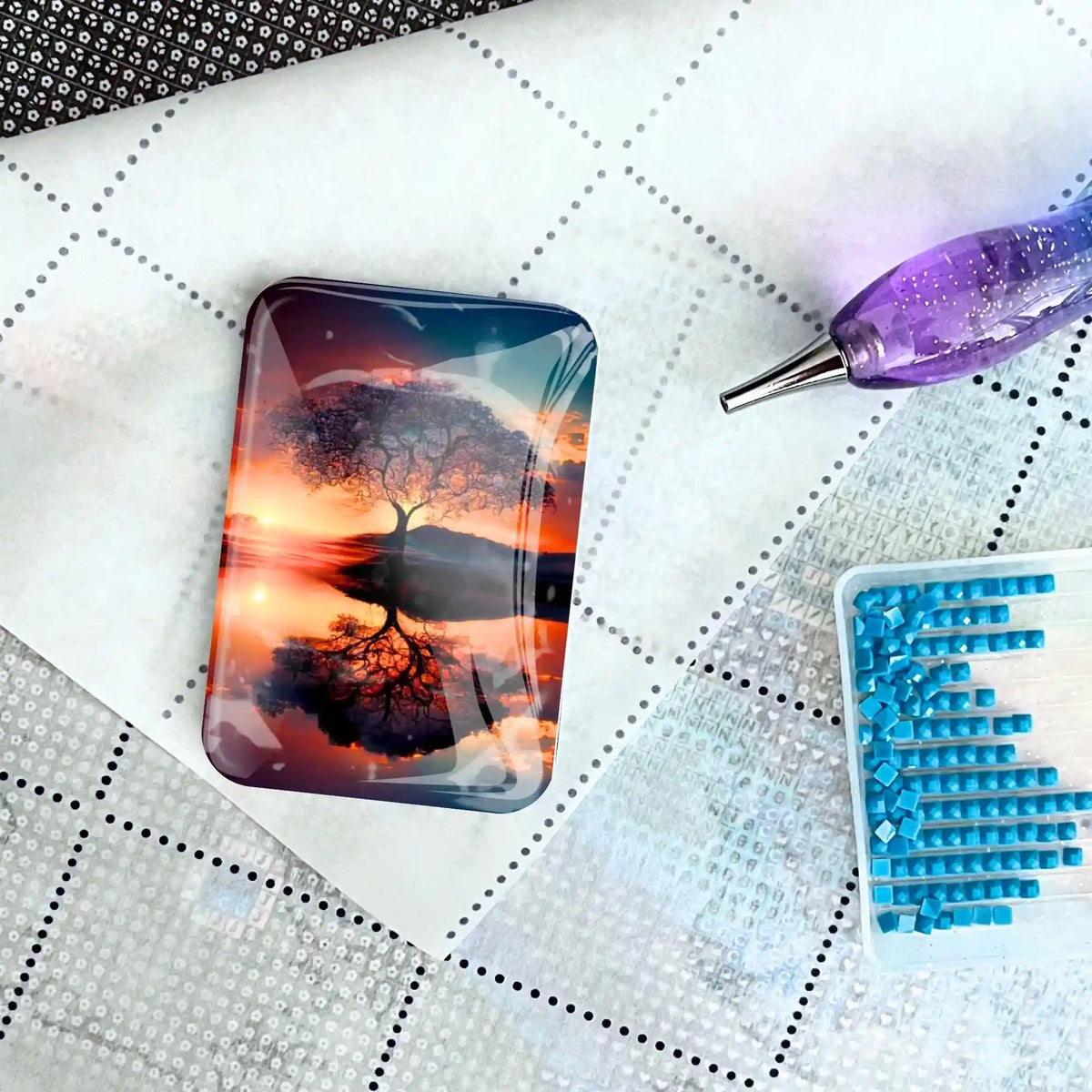 Diamond Painting Cover Minder mit Baum im Sonnenuntergang Motiv auf einer Leinwand mit Stift und Glitzersteinen