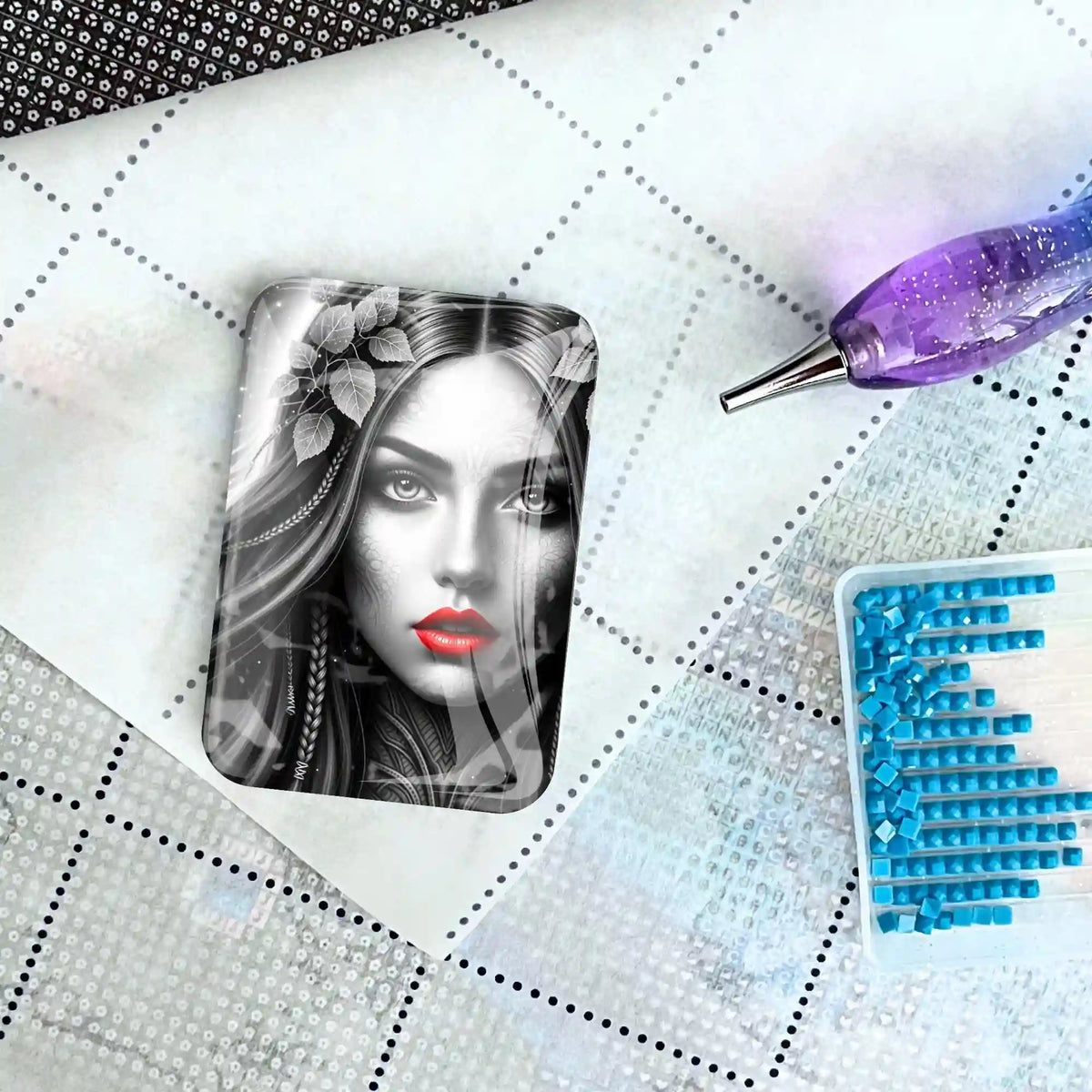 Diamond Painting Cover Minder mit Red Lips Motiv auf Leinwand, daneben Stift und blaue Steinchen im Set