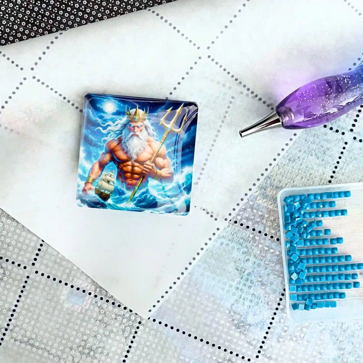 Quadratischer Poseidon Cover Minder aus Glas als praktisches Zubehör für Diamond Painting auf einer Leinwand.