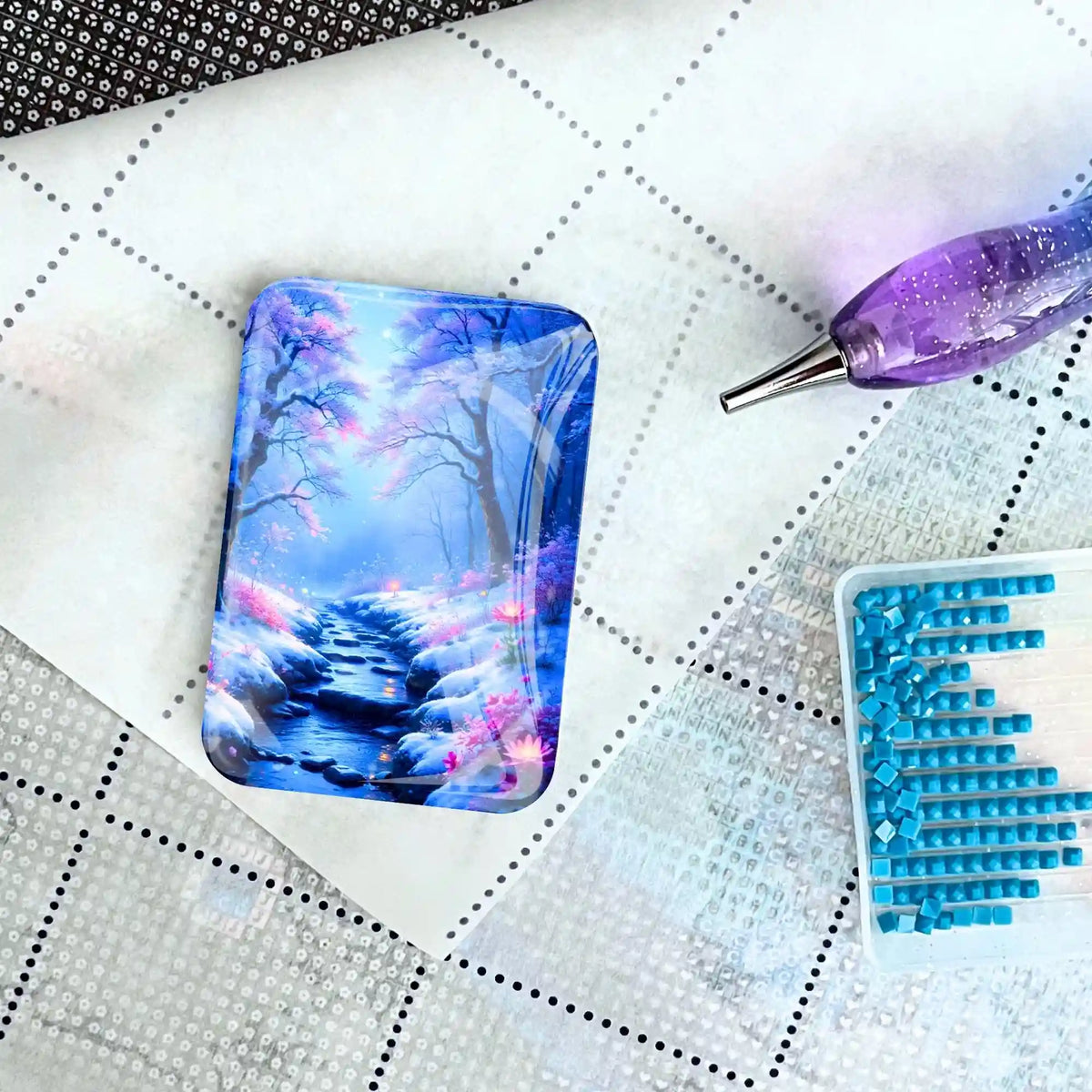 Magischer Cover Minder mit Motiv Fluss der Träume auf einer Diamond Painting Leinwand mit Glitzer-Stift und Steinchen.