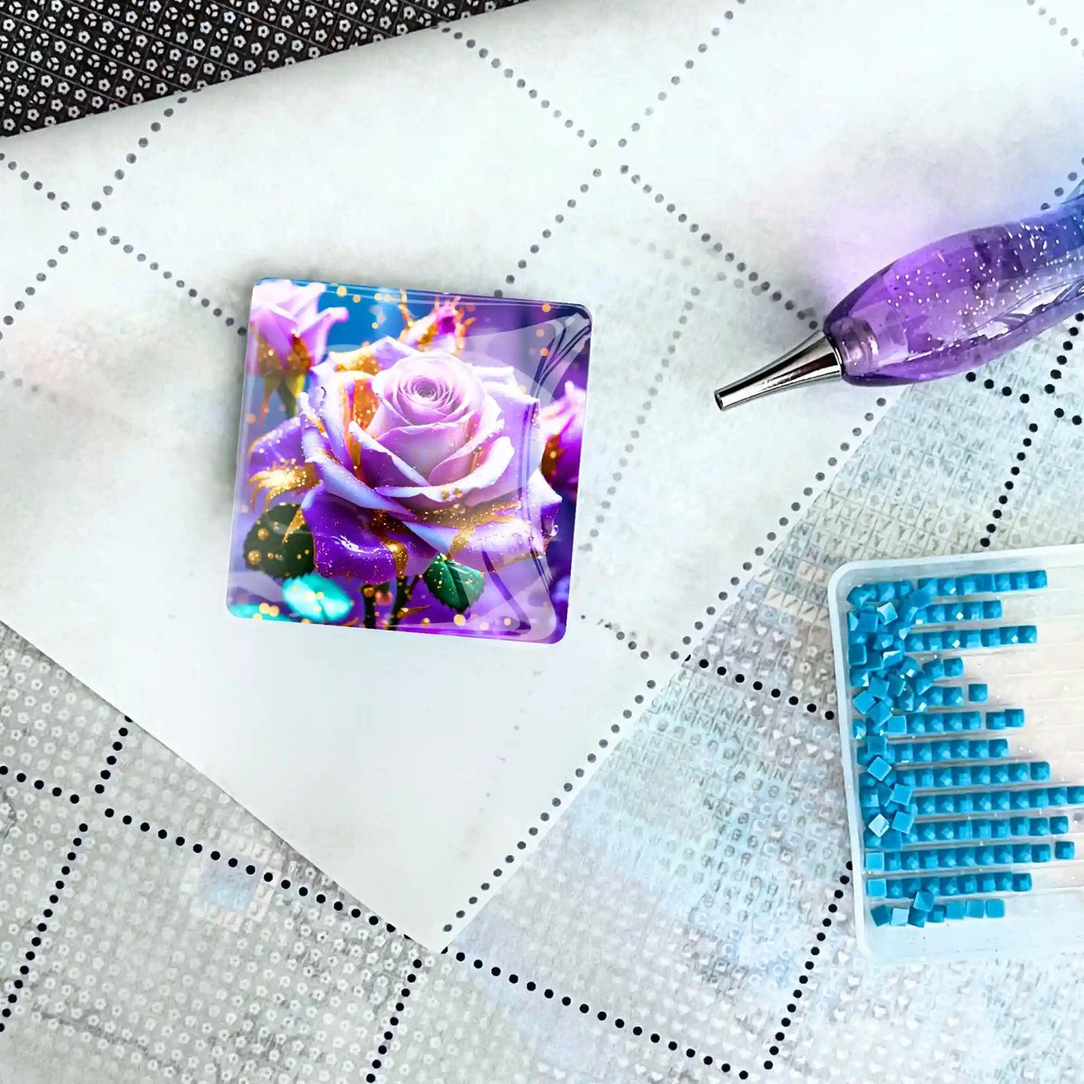 Quadratischer Amethystrose Cover Minder für Diamond Painting Zubehör auf weißer Leinwand mit Stift und blauen Steinchen