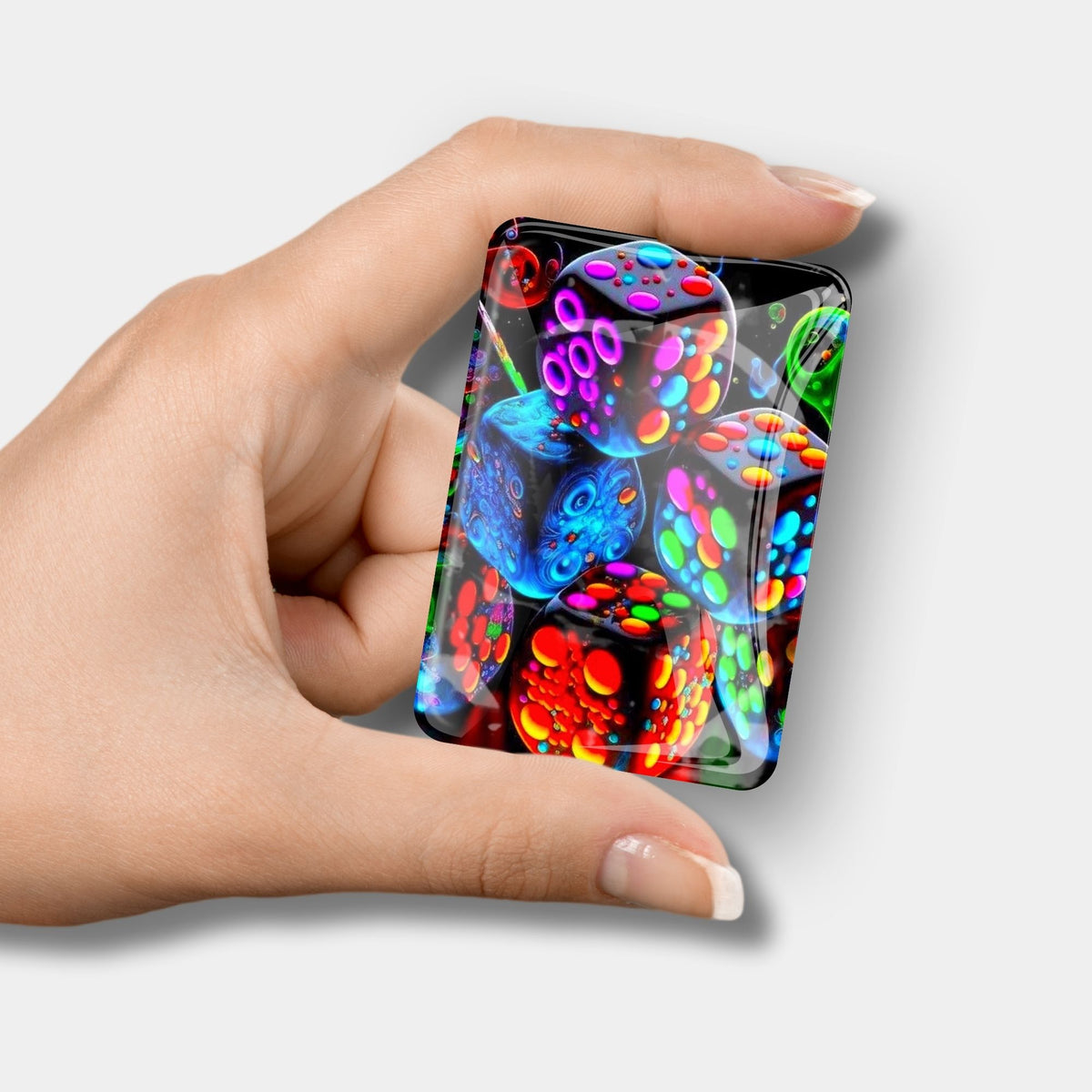Glas Cover Minder mit buntem Würfel-Motiv als praktisches Diamond Painting Zubehör in einer Hand gehalten.
