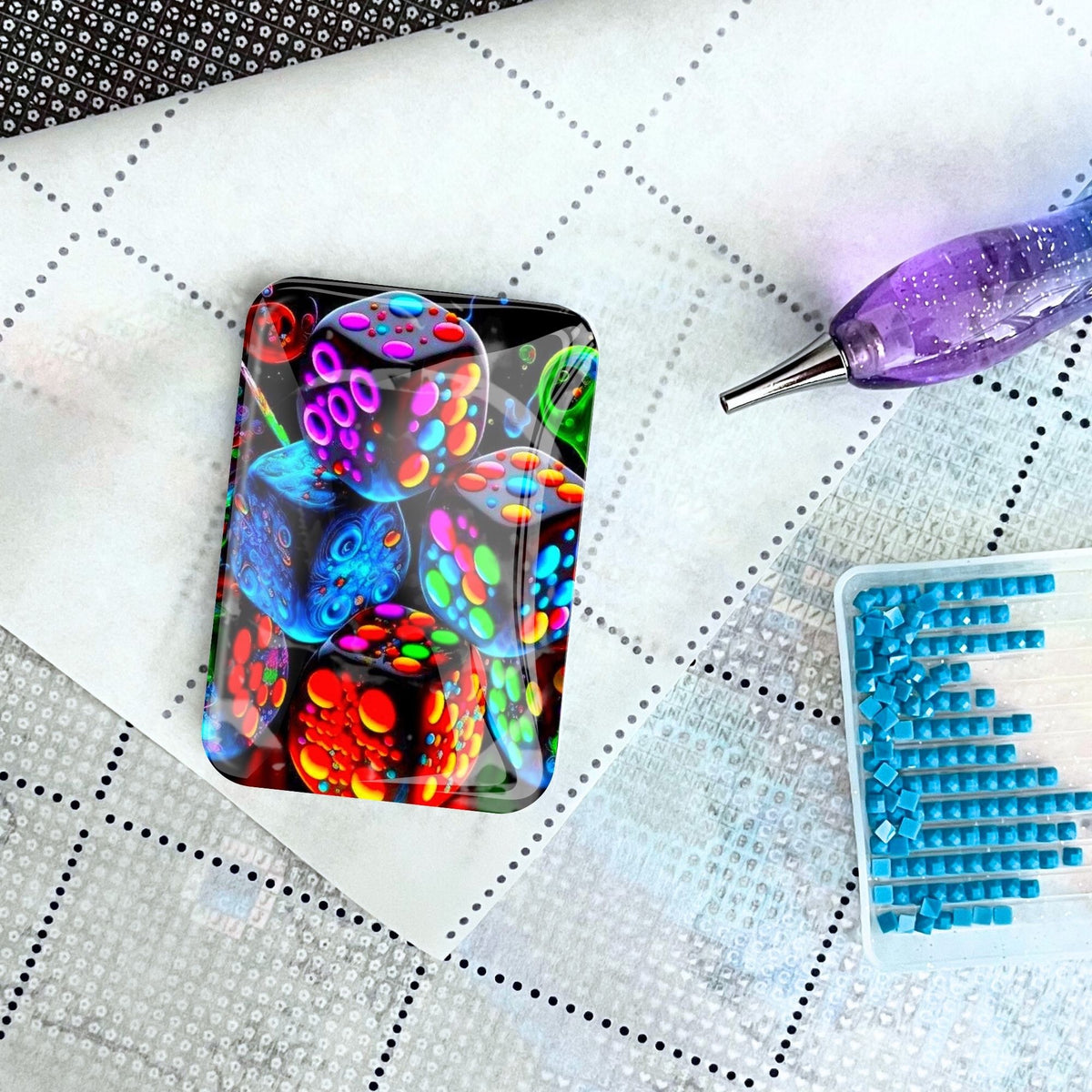Glas Cover Minder mit Würfel-Motiv als nützliches Accessoire für Diamond Painting auf einer Leinwand mit Steinchen.