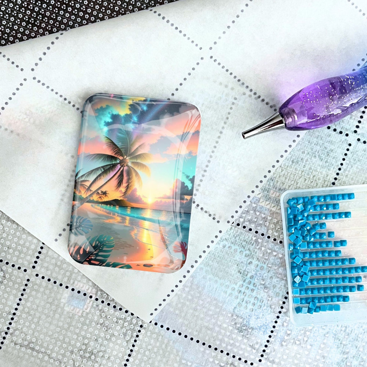 Glas Cover Minder mit Palmenmotiv für Diamond Painting auf einer Leinwand mit Stift und blauen Diamanten