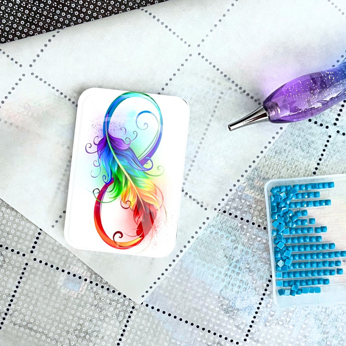 Bunter Infinity Feather Cover Minder aus Glas als Zubehör für Diamond Painting auf einer Leinwand mit Stift und Steinen
