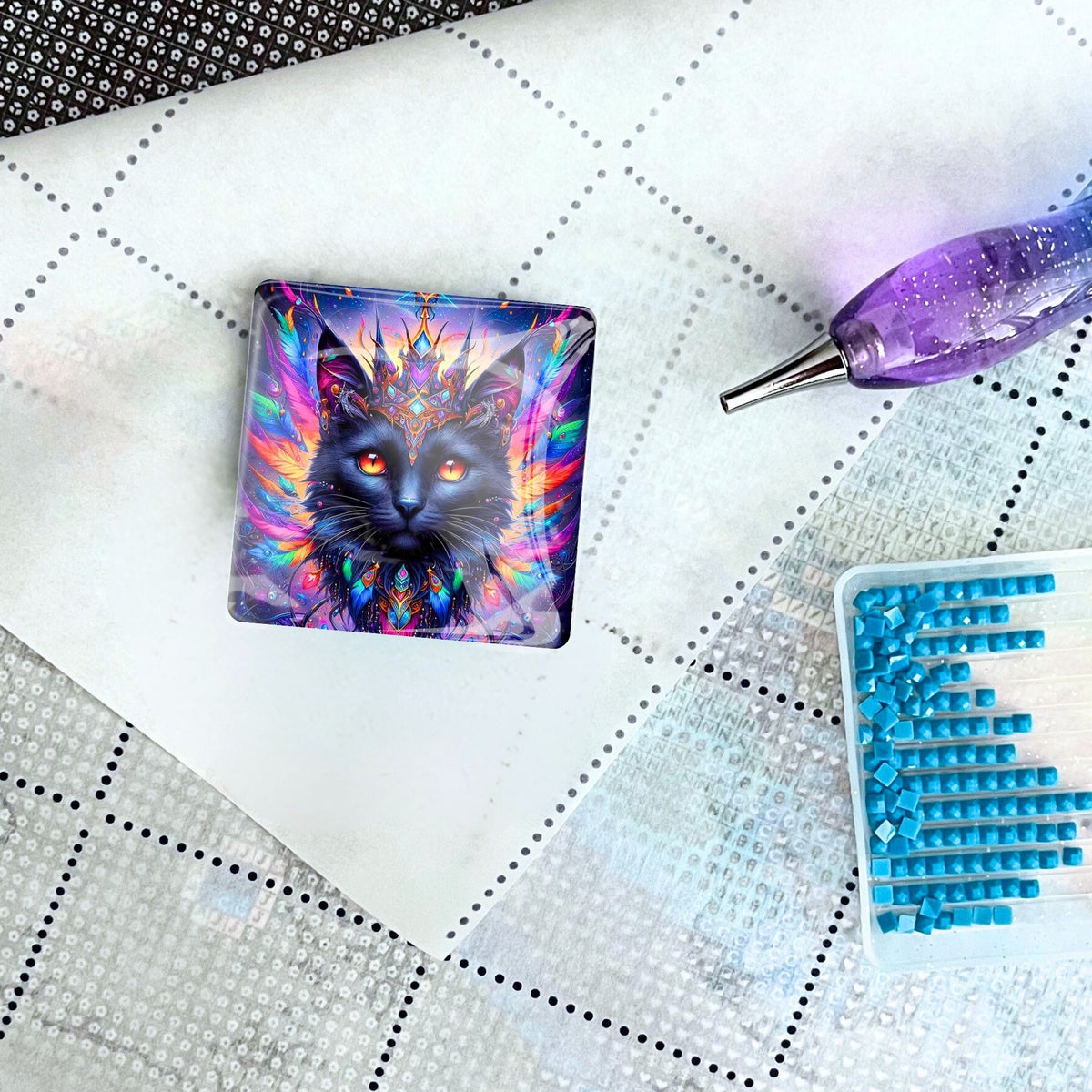 Diamond Painting Cover Minder mit buntem Katzen-Motiv, platziert auf einer Leinwand mit Stift und blauen Diamanten