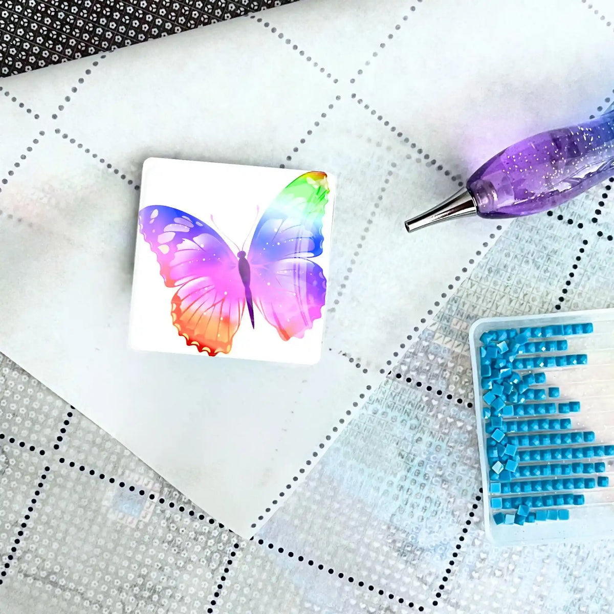 Bunter Schmetterling Cover Minder aus Glas als praktisches Zubehör für Diamond Painting auf einer Leinwand mit Stift.