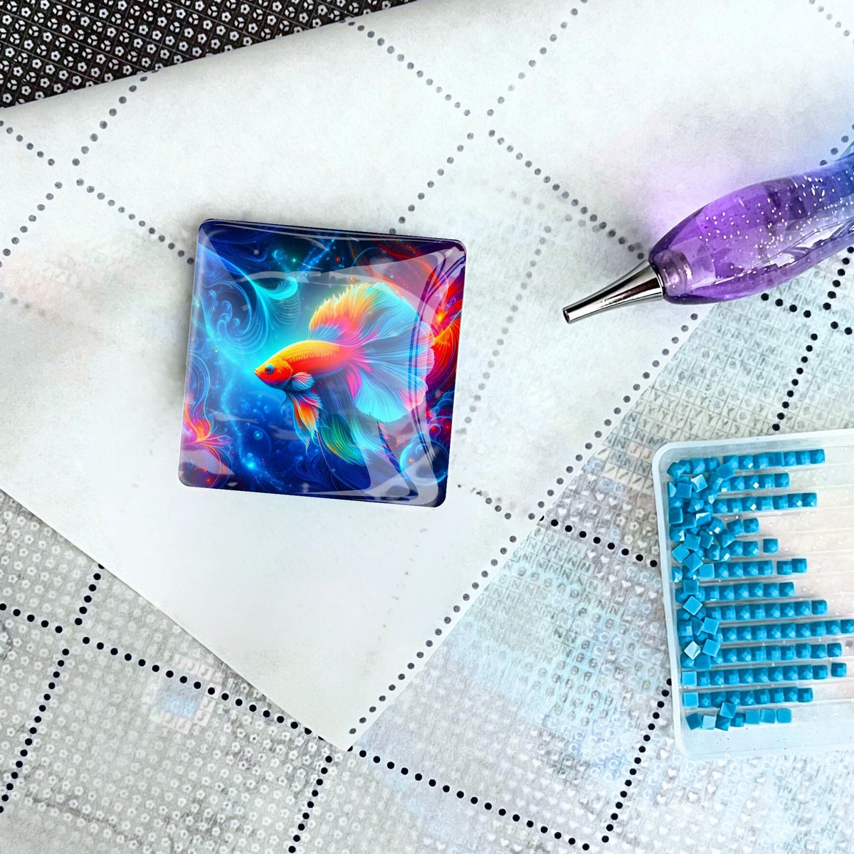 Quadratischer Diamond Painting Cover Minder mit buntem Fisch-Motiv auf einer Leinwand mit Steinchen und Set-Zubehör.