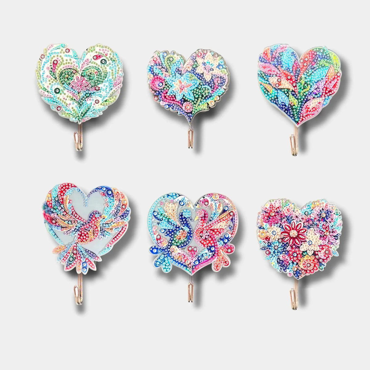 Sechs funkelnde Diamond Painting Wandhaken in herzförmigen Mosaik-Designs mit bunten Steinchen für kreative DIY-Wanddeko.