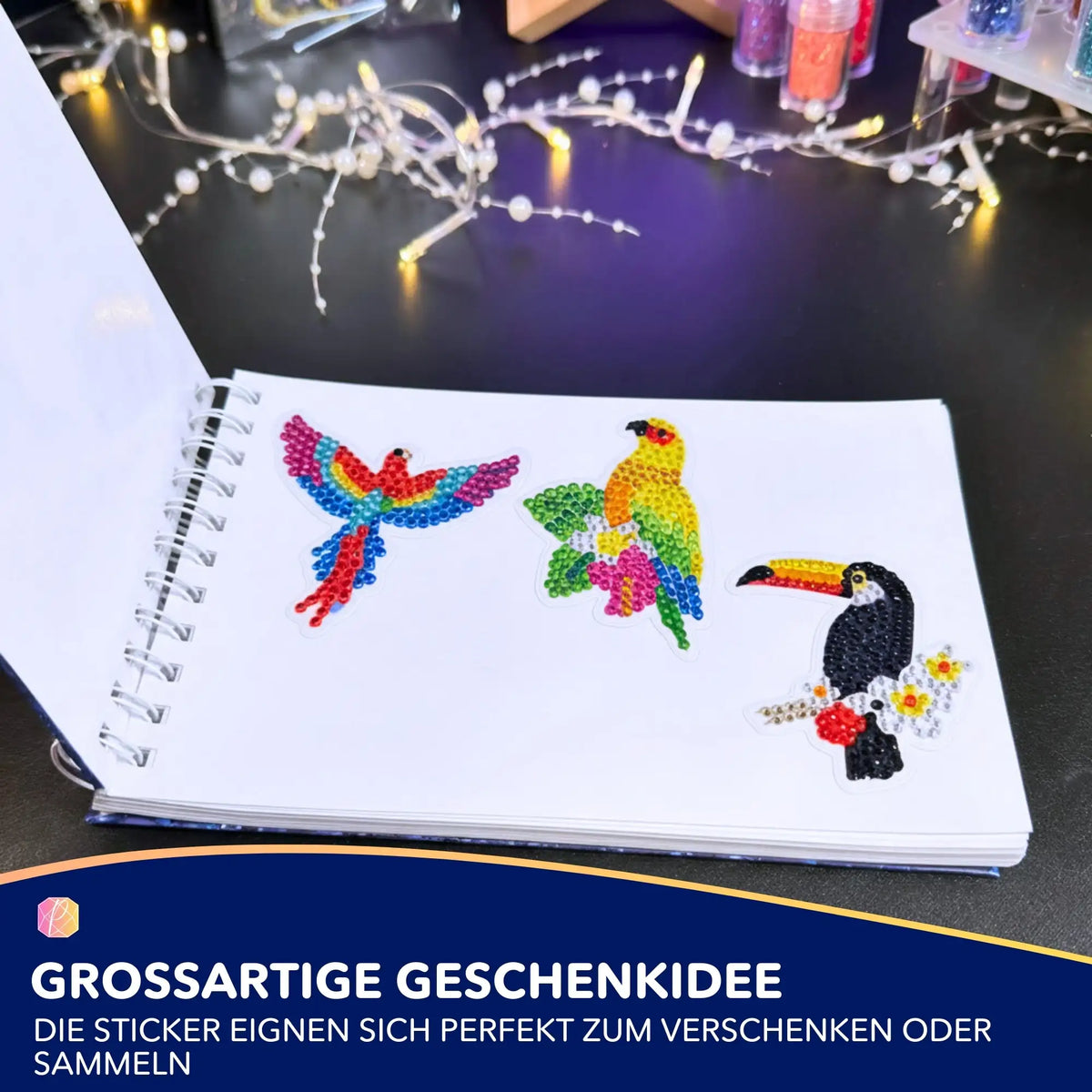 Drei bunte Diamond Painting Sticker mit Vogelmotiven auf einem Block klebend.
