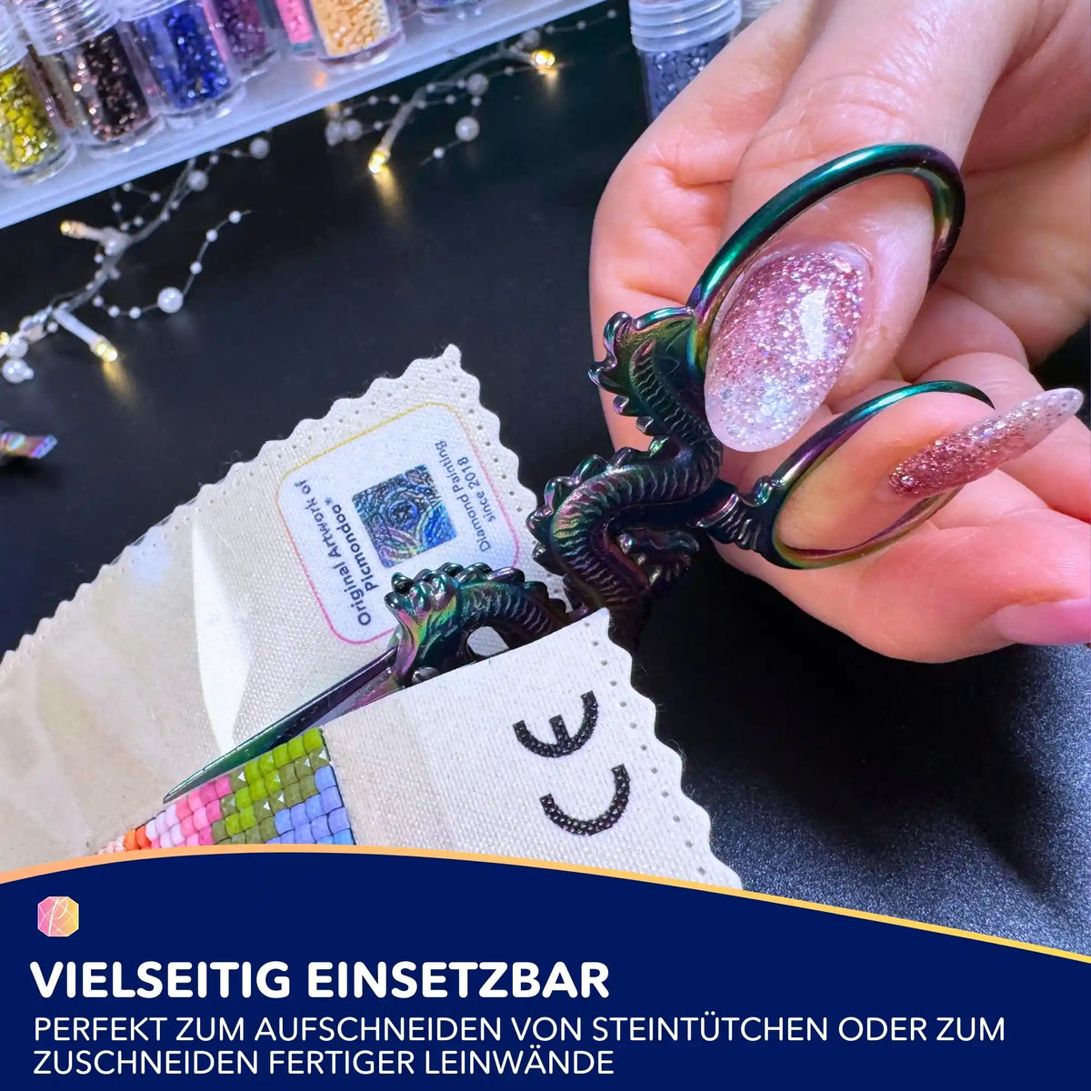 Diamond Painting Schere im regenbogenfarbenen Drachen-Design zum Zuschneiden von Leinwänden und Steinchen-Tütchen.