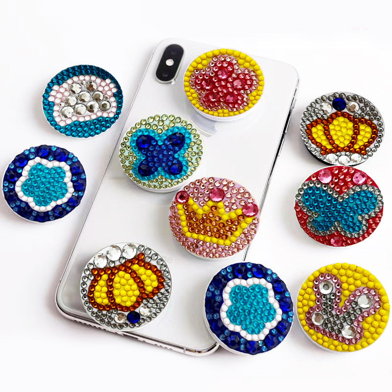Smartphone mit verschiedenen bunten Diamond Painting Pop-Griffen mit Motiven wie Krone, Blume und Schmetterling.